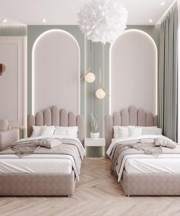 Modern twin bedroom with plush scalloped beige headboards, white and neutral bedding, floating nightstand with plant, pendant lights, arched alcove wall design, chandelier, herringbone wood flooring, and muted green curtains